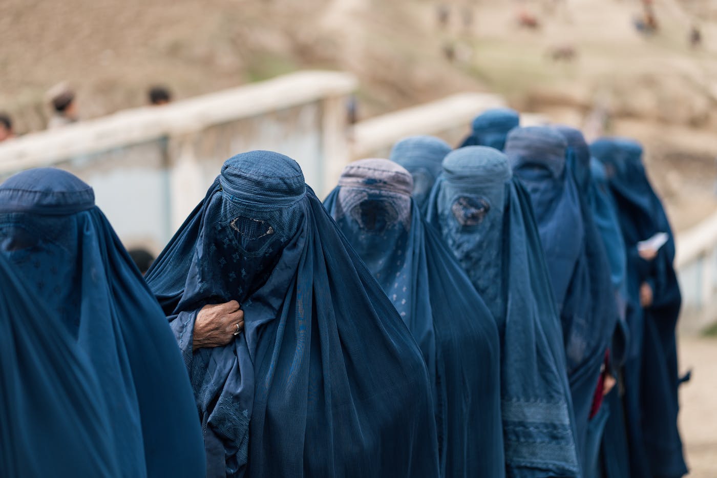 Line of women in traditional blue chadari outdoors — dignity, visibility, and protection in public space.